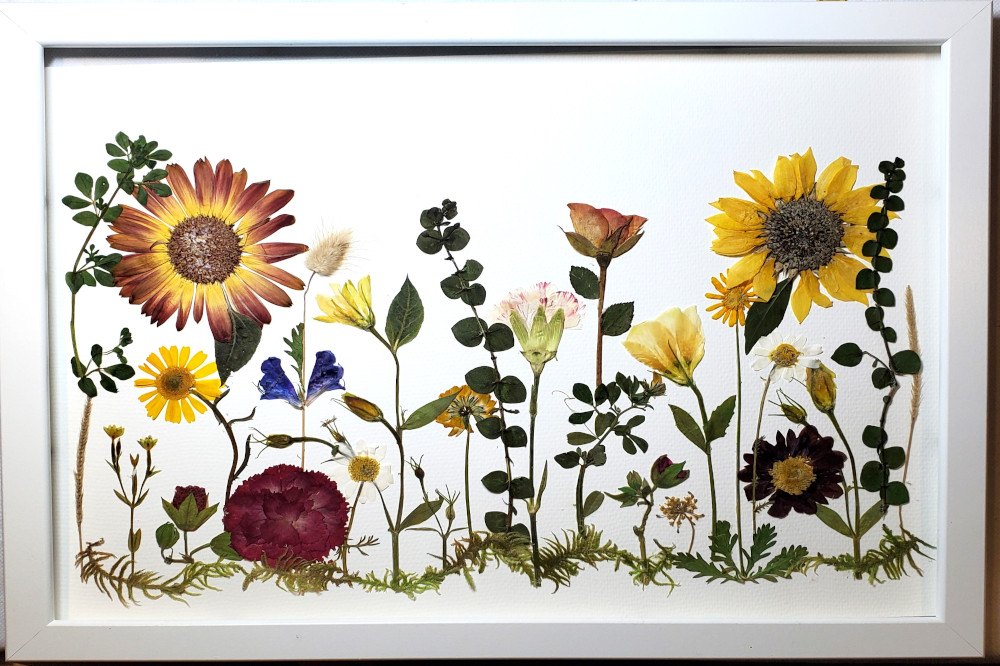 A handmade artwork featuring dry-pressed flowers arranged on a white canvas, created during a creative workshop in Porto, Portugal.